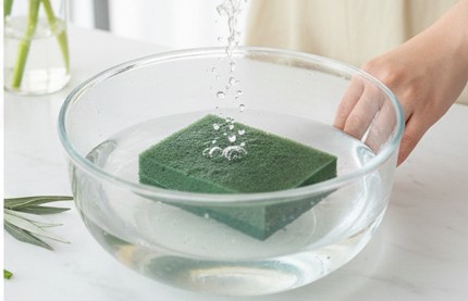 バケツの水に浮かべて自然吸水させている園芸用オアシスの様子（手で押し込まない正しい方法）