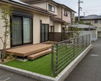メンテナンスフリーな人工芝と樹脂製ウッドデッキで整えられた快適な庭