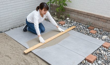 外構タイルを置く前に砂の下地を木の板で平らにならす整地作業の様子