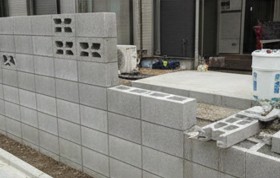 住宅街でコンクリートブロックを丁寧に積み上げる施工の様子