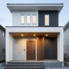 夕暮れ時にライトアップされたおしゃれなシンプルモダンの玄関ポーチと外構デザイン