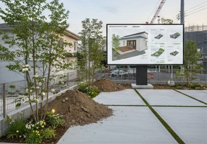 きこりん税と呼ばれる諸経費の仕組みを庭にディスプレイを置いて表示している様子