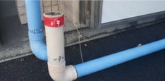 外構工事の現場で、規定の深さに埋設された電気配管（PF管）の上に、注意喚起のための埋設標識シートが敷設されている様子