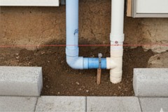 外壁の色に合わせて設置されたベージュや濃茶色のPF管のクローズアップ。屋外配線を保護するために外壁に固定されている